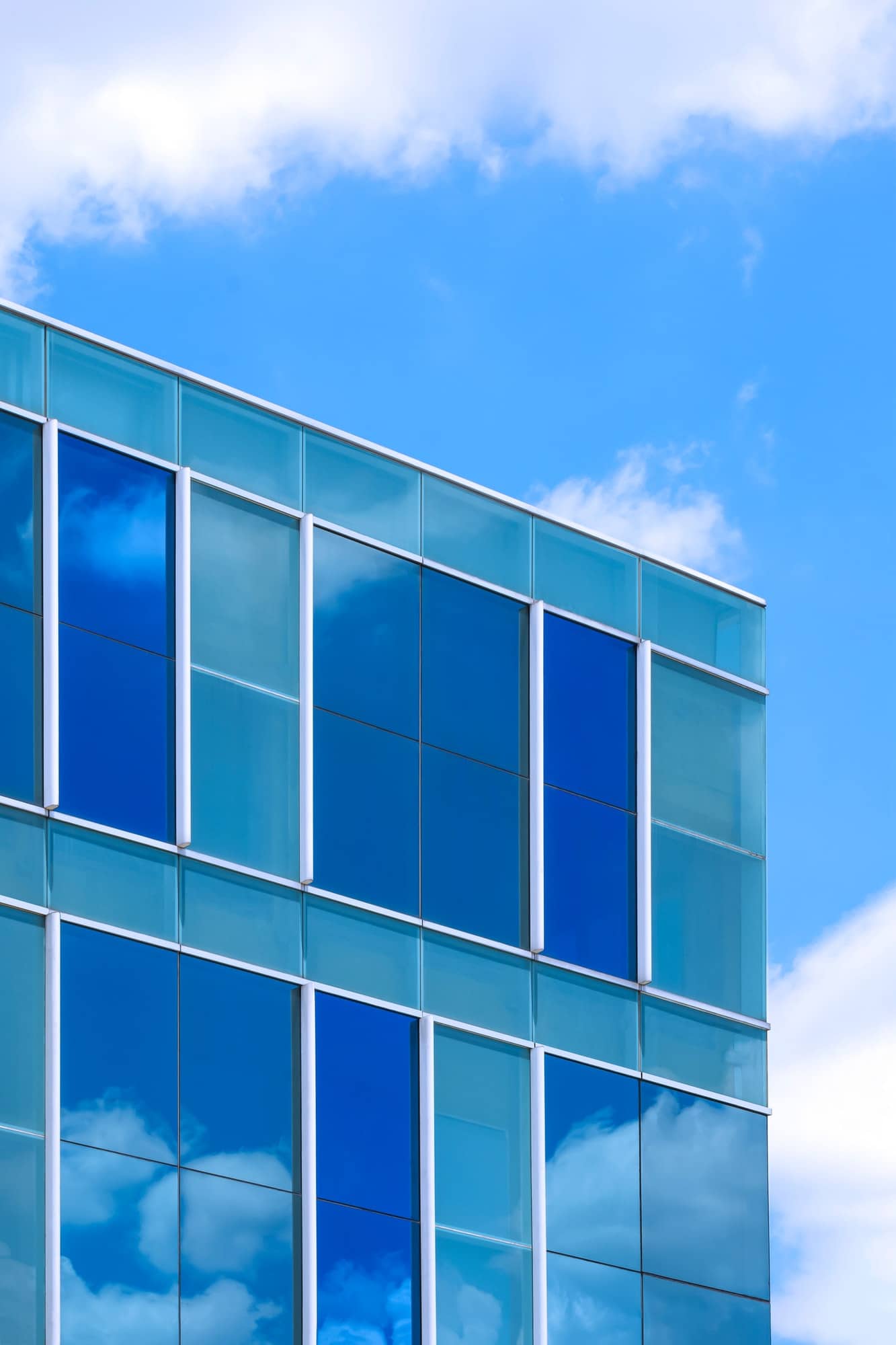 Stunning reflection on surface of modern glass office building against blue sky background